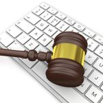 Wooden gavel on computer keyboard, symbol of law and justice in technology